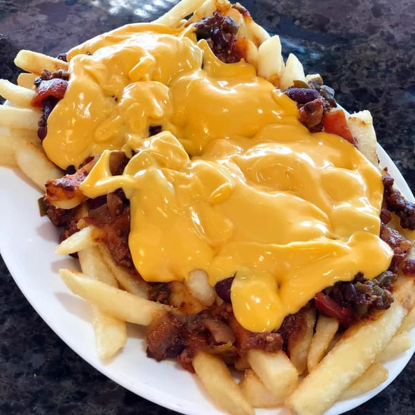 A plate of golden french fries covered in chili and melted yellow cheese from Lighthouse Diner.
